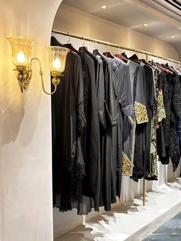 Garment rail lit by brass sconces against textured plaster at ARRV