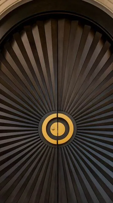 Arched main door with radiating dark timber fins and brass centre