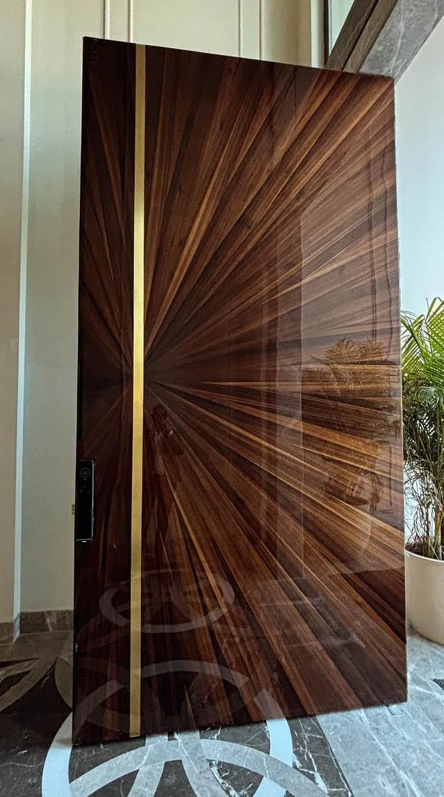 Pivot door with book-matched sunburst veneer and brass inlay